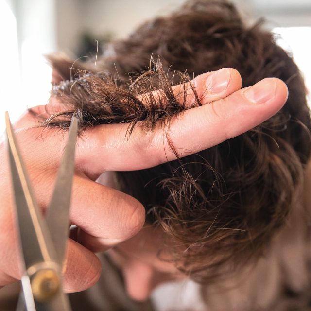 Stylist cutting a client's curly hair with scissors in a bright studio